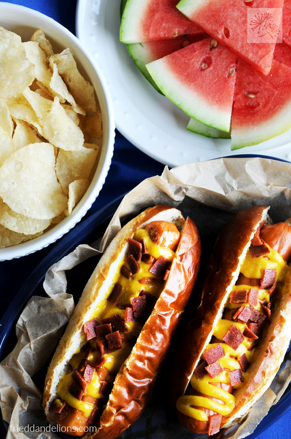 30 Best camping meals ever! two hot dogs with bacon pieces on top, potato chips and water melon in the background