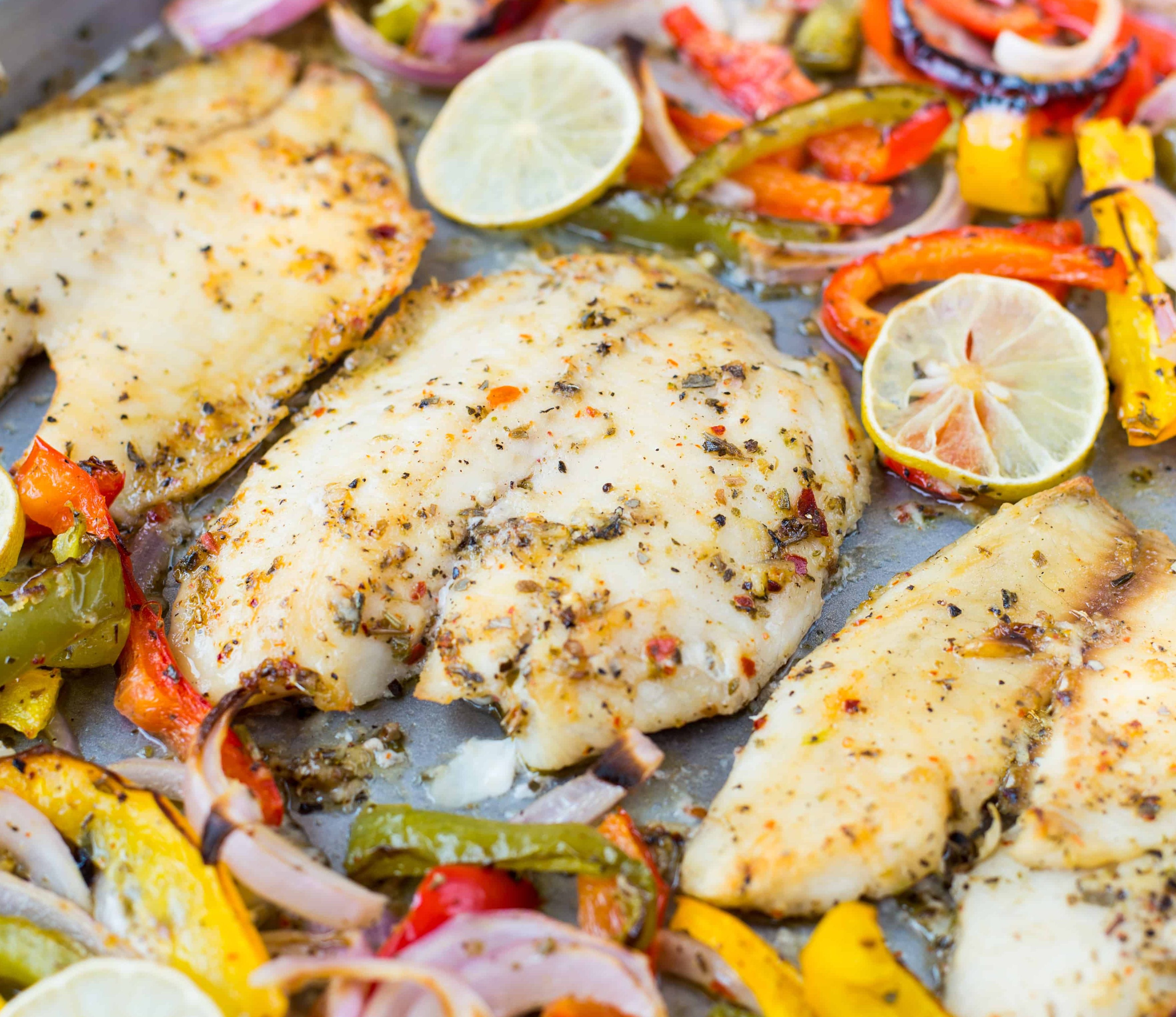 Tilapia fish with peppers and lemon rounds on a pan. Sheet Pan Dinner Options.